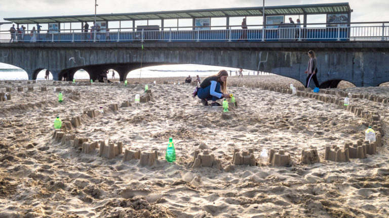 Asha building the Plastic Pathways Beach labyrinth on the sand for Arts by the Sea festival by artist Michelle Rumney